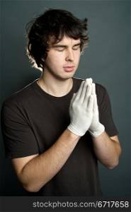 An image of a young man in gloves praying