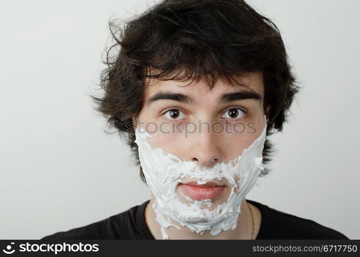 An image of a young man with shaving foam on his face