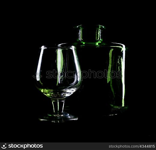 An image of glass with bottle on black