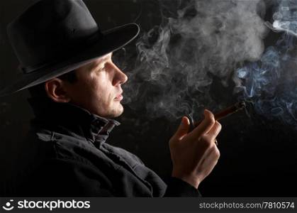 An image of man in felt hat in dark room