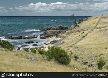 An image of the australian coast with rock, sand and the sea