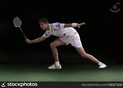 An Indian male badminton player playing over black background