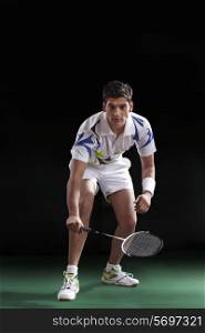 An Indian male player in sportswear playing badminton over black background