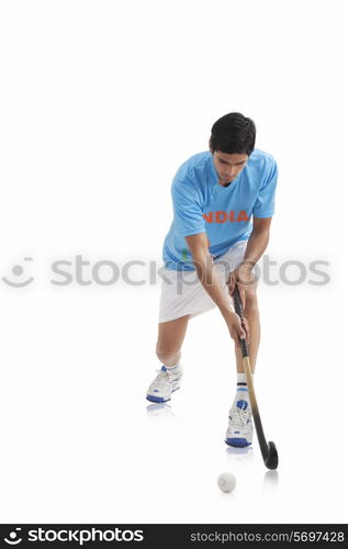 An Indian male player playing hockey isolated over white background