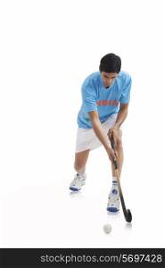 An Indian male player playing hockey isolated over white background