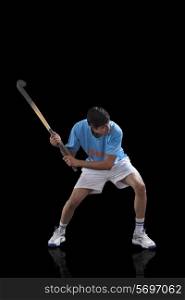 An Indian sportsman practicing hockey isolated over black background