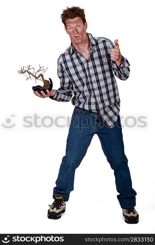 An injured man holding a dead plant.