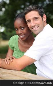 An interracial couple in a park.