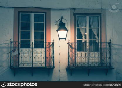 An intriguing night scene of an old European city street with a lonely vintage lantern on the wall of the house.