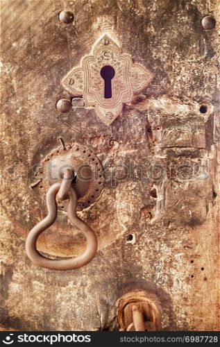 An iron door knocker and a keyhole adorn a battered wooden door at the Dambulla cave temple in Sri Lanka