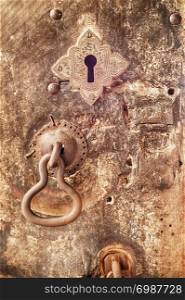 An iron door knocker and a keyhole adorn a battered wooden door at the Dambulla cave temple in Sri Lanka