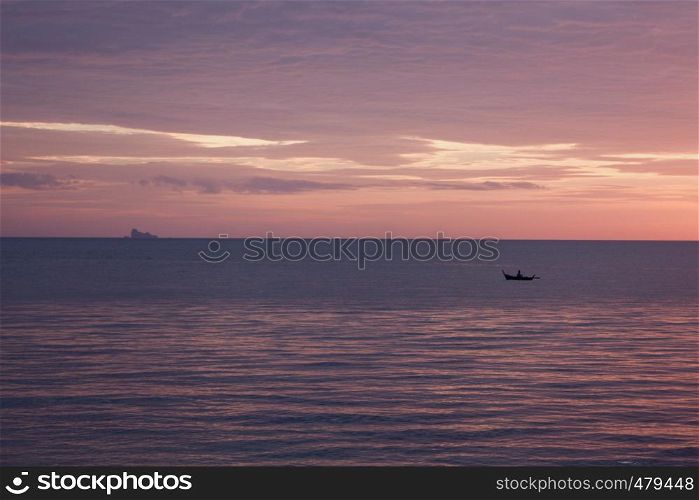 An islander paddles a dug out canoe in Thailand at sunset