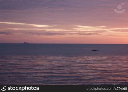 An islander paddles a dug out canoe in Thailand at sunset