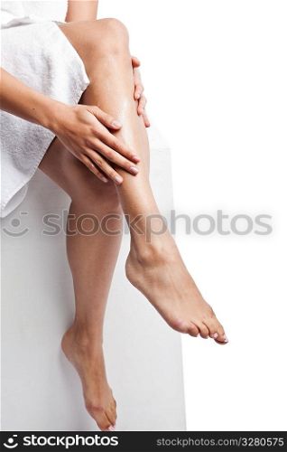An isolated shot of a beautiful black woman applying lotion on her legs