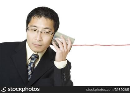 An isolated shot of a businessman listening to a tin can phone