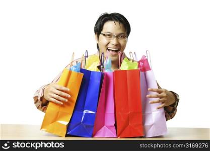 An isolated shot of a happy young man with shopping bags and gifts