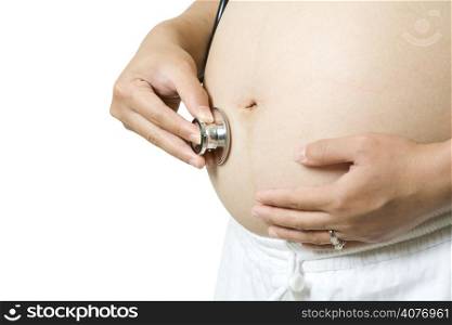 An isolated shot of a pregnant woman using a stethoscope to listen to her baby&acute;s heartbeat