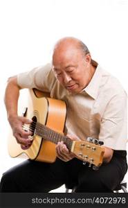 An isolated shot of a senior asian man playing guitar