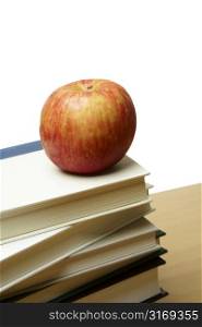 An isolated shot of an apple on top of a pile of books