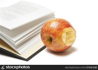 An isolated shot of an open book and an apple
