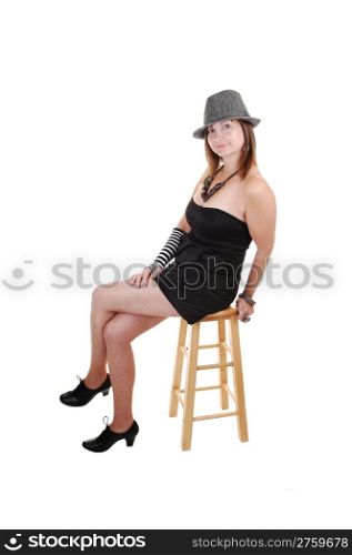 An middle aged woman in an short black dress and a gray hatsitting for a portrait shot in the studio, for white background.