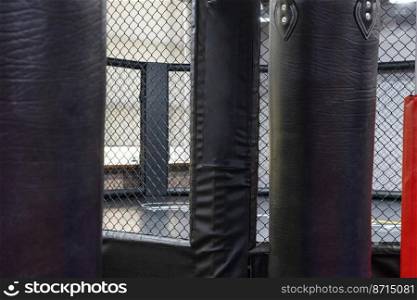 An octagonal kickboxing cage with boxing bags in the sports complex. Octagonal kickboxing cage with boxing bags in the sports complex