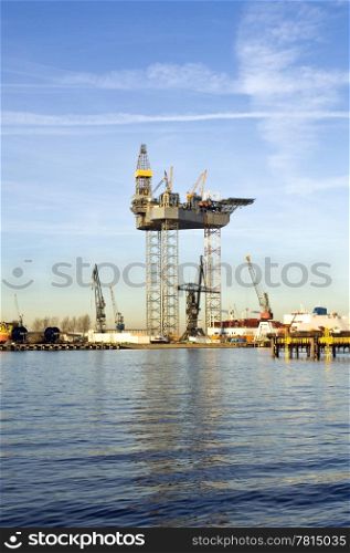 An oil rig is being constructed in a harbor area, to be towed to sea after completion.