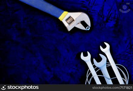 An old adjustable wrench teaches skill and provides food for new open-end wrenches, classic dark blue color background. The concept of communication and training, image with copy space.. An old adjustable wrench teaches the lives of new wrenches. The concept of communication and learning.