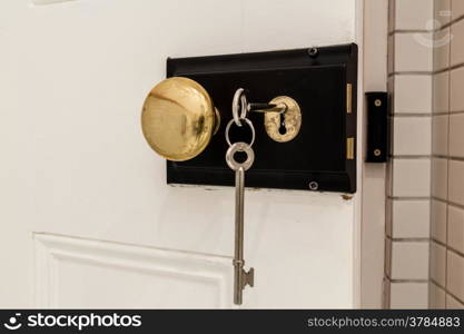 An old antique door lock with long keys and a round knob