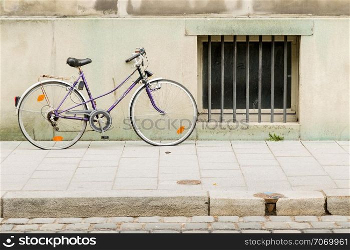An old bicycle leaning on wall in city building