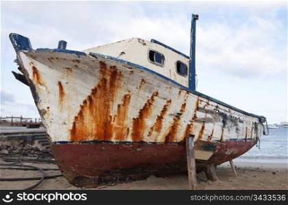 An old boat, weathered by the elements, is pulled up on the beach in the harbor of Puerto Baquerizo Moreno on the Galapagos Islands.