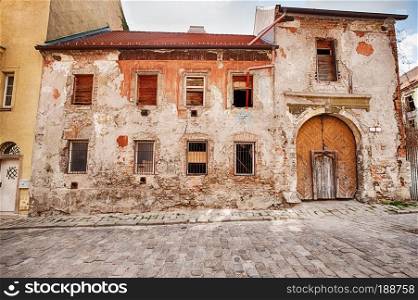 An old building with a large wooden door entrance that is in need of repairs stands next to a street of cobblestones in the Old Town  Stare Mesto  of Bratislava in Slovakia.