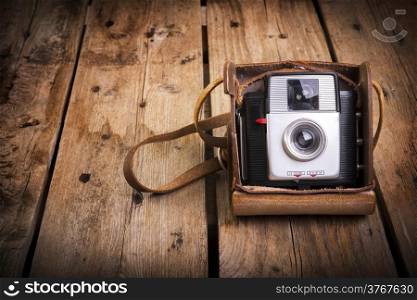 An old camera in its original vintage leather case on a wooden background