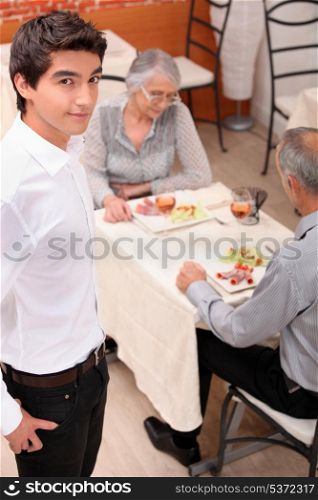 an old couple eating at restaurant and a young waiter