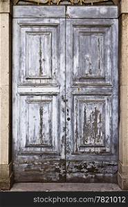 An old door with gray paint that has weathered into a remarkable texture.