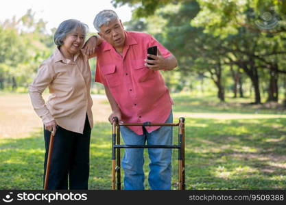 An old elderly Asian man uses walker and use smartphone for taking photos with his wife.  Concept of happy retirement With Love and care from family and caregiver, Savings, and senior health insurance