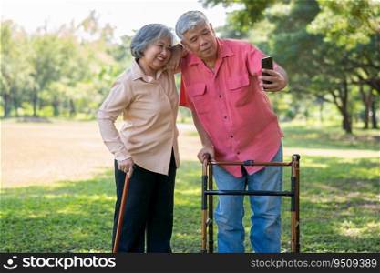 An old elderly Asian man uses walker and use smartphone for taking photos with his wife.  Concept of happy retirement With Love and care from family and caregiver, Savings, and senior health insurance