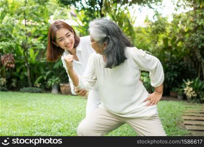 An old elderly Asian woman and exercise in the backyard with her daughter. Concept of happy retirement With care from a caregiver and Savings and senior health insurance, Happy family