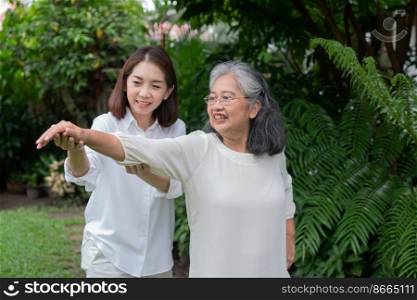 An old elderly Asian woman and exercise in the backyard with her daughter.  Concept of happy retirement With care from a caregiver and Savings and senior health insurance, Happy family