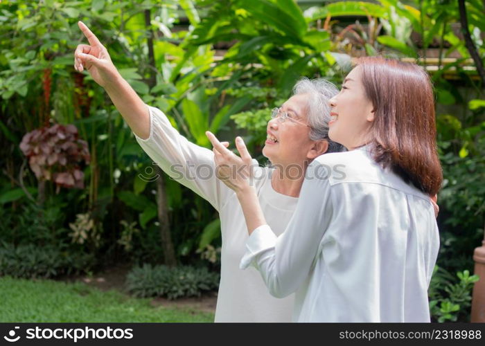 An old elderly Asian woman and walking in the backyard with her daughter. Concept of happy retirement With care from a caregiver and Savings and senior health insurance, Happy family