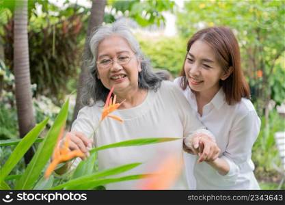An old elderly Asian woman and walking in the backyard with her daughter.  Concept of happy retirement With care from a caregiver and Savings and senior health insurance, Happy family