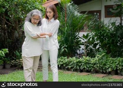 An old elderly Asian woman and walking in the backyard with her daughter.  Concept of happy retirement With care from a caregiver and Savings and senior health insurance, Happy family