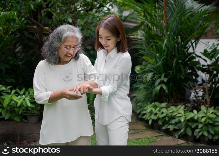An old elderly Asian woman and walking in the backyard with her daughter. Concept of happy retirement With care from a caregiver and Savings and senior health insurance, Happy family