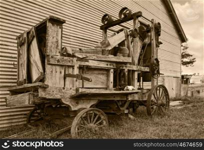 an old farm machinery baler in sepia