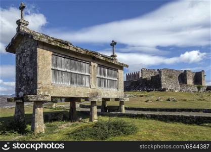 An old Granary (espigueiros) and castle above the village of Lindoso in the Parque Nacional da Peneda-Geres in northern Portugal. Grain could be stored in cool, well ventilated, dry conditions and at the right humidity. The unique pedistal design is to keep rodents out.
