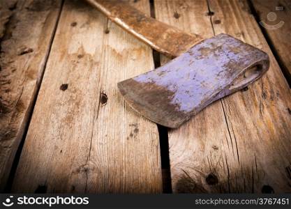 An old hatchet axe with a wooden handle and wear marks sits on a rough timber background