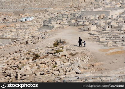 An old man and his grandson are walking down the cemetery in the Kidron Valley in Jerusalem, Israel