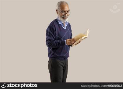 AN OLD MAN HAPPILY LOOKING AT CAMERA WHILE READING