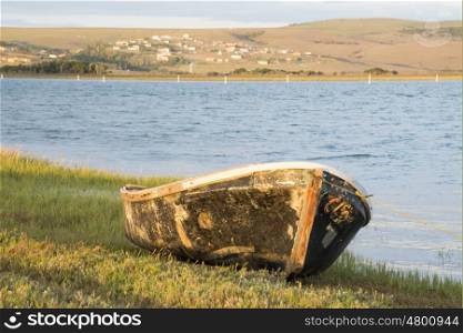 An old neglected boat lies tied with a roap on the bank of the river.