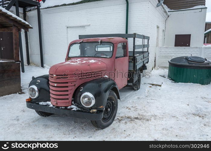 An old red truck on a winter day in the village of Vyatsky, Yaroslavl Region, Russia.